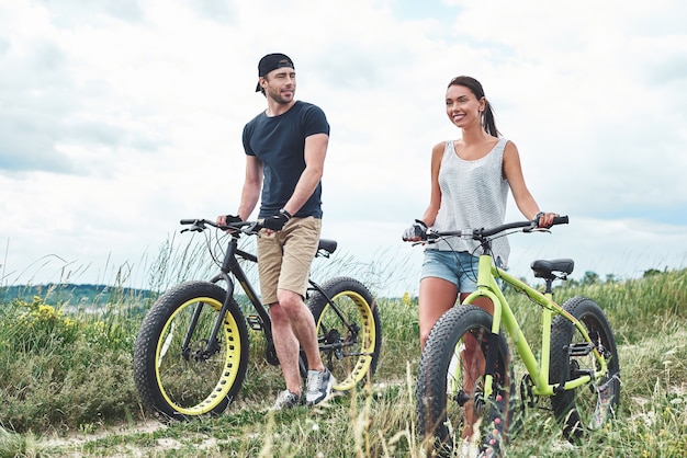 Young man looks at young beautiful woman with fatbike