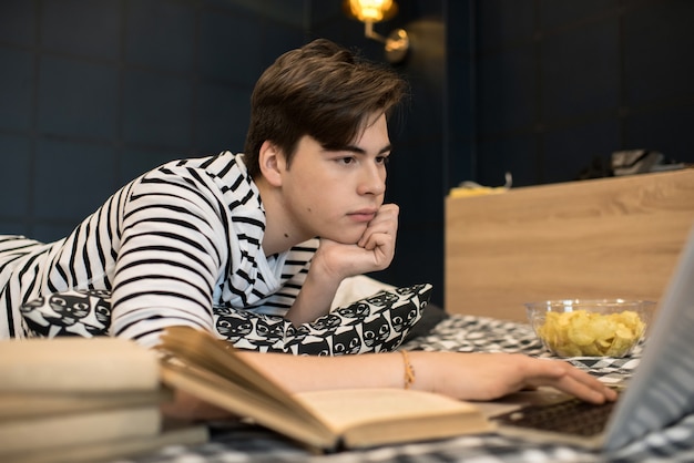 Young man lying on bed using laptop