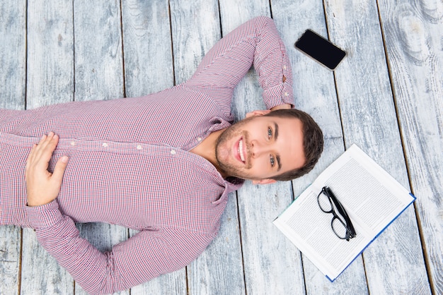 Young man lying on the floor with book