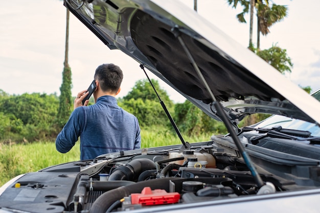 Young man make a phone call during car broken. Man need help.