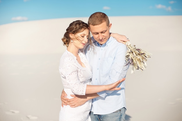 Photo young man makes marriage proposal to his girlfriend for a romantic date in the open air in the sand dunes.