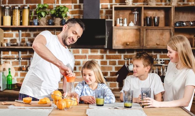 Young man makes orange juice for his family for breakfast