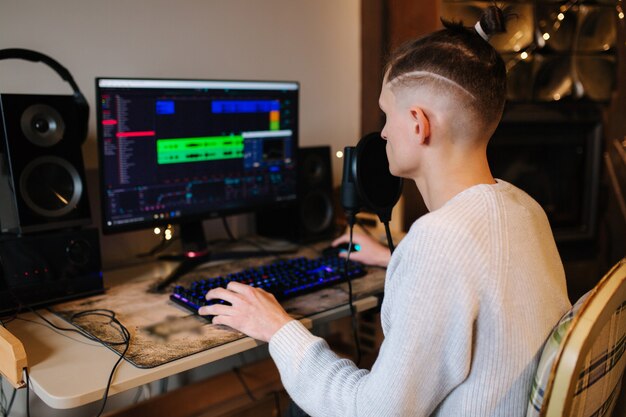 젊은 남자가 PC와 두 개의 전문 마이크를 사용하여 집에서 팟 캐스트 오디오 녹음을 만듭니다.