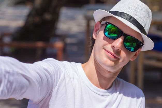 Photo young man making his selfie on beach at outdorr cafe