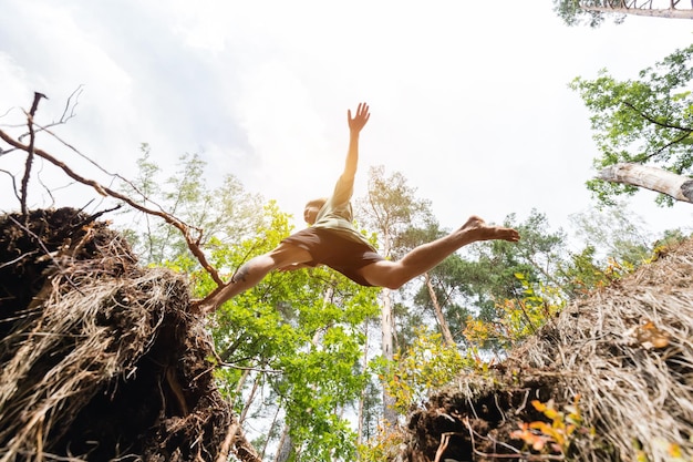 Photo young man making a jump in the forest freedom concept low angle perspective