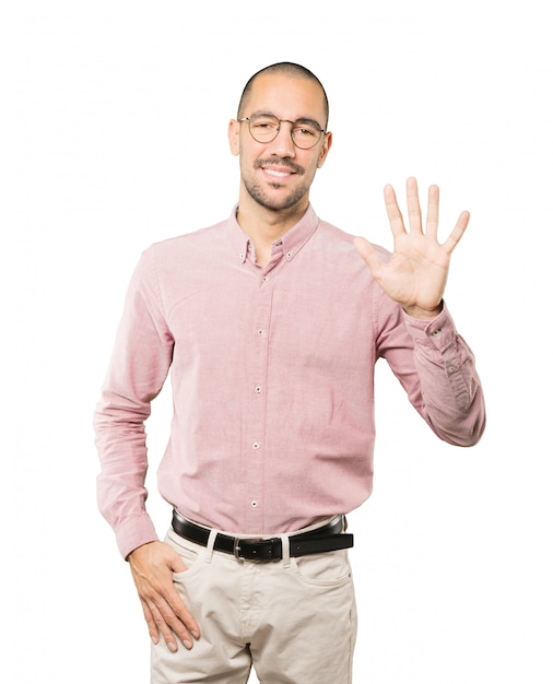 Young man making a number five gesture