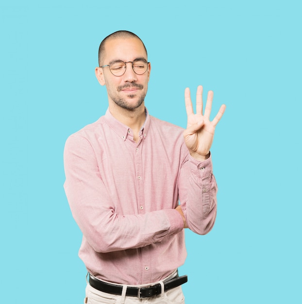 Young man making a number four gesture