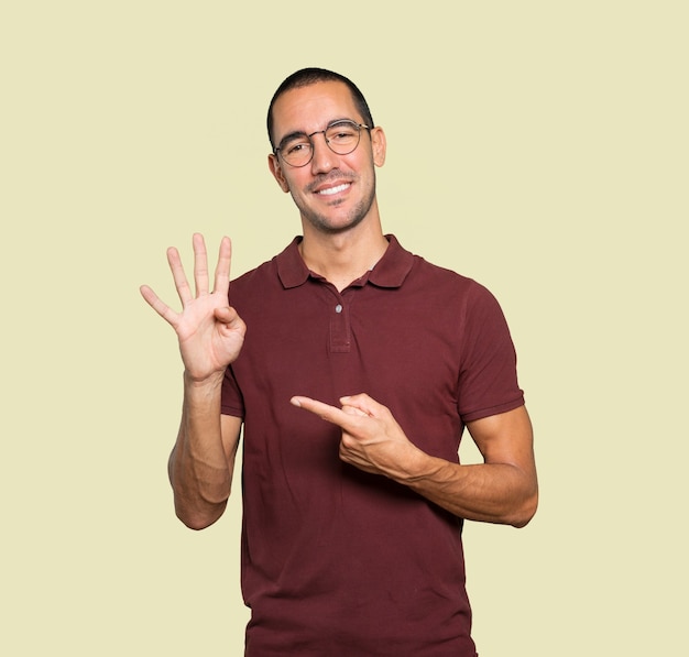 Young man making a number four gesture