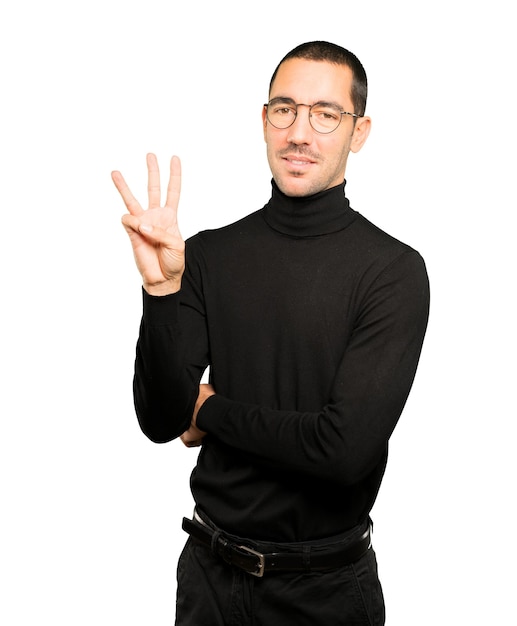 Young man making a number three gesture