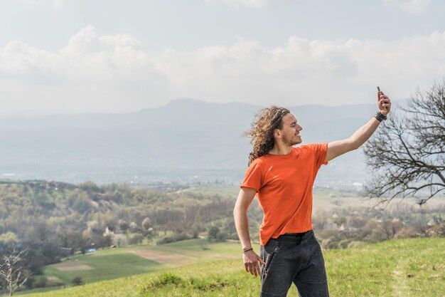 Photo young man making selfie on mobile phone on the hill