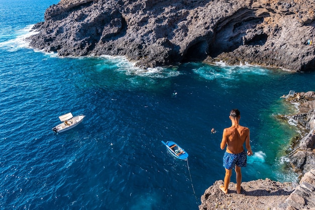 Un giovane uomo che fa un salto molto alto in acqua nella città di poris de candelaria, sulla costa nord-occidentale dell'isola di la palma