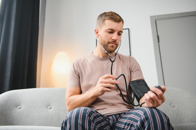 Young man measuring his blood pressure at home