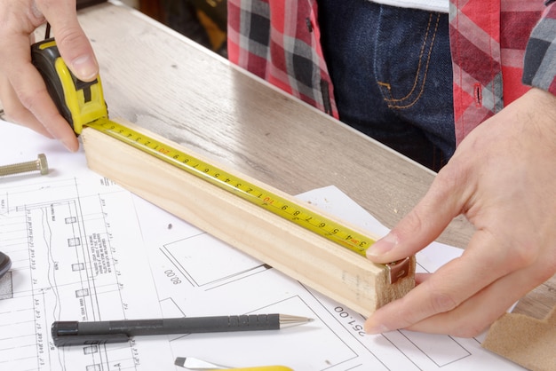 Young man measuring wooden board