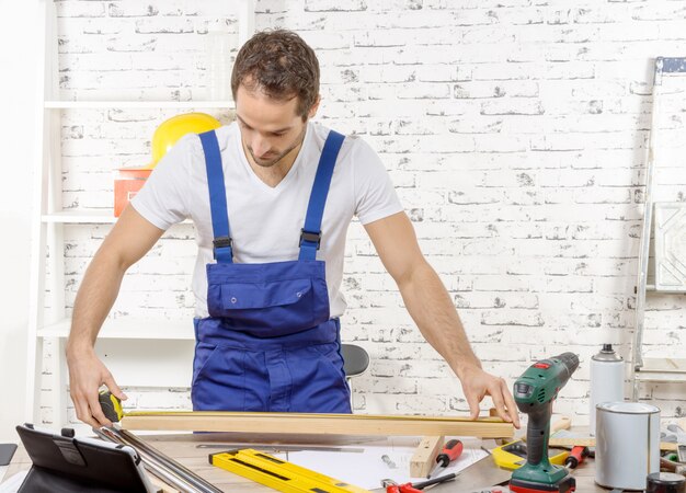 Young man measuring wooden board