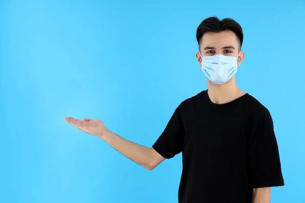 Young man in medical mask on blue background