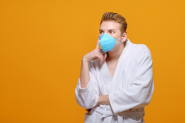 Young man in medical mask and housecoat in quarantine