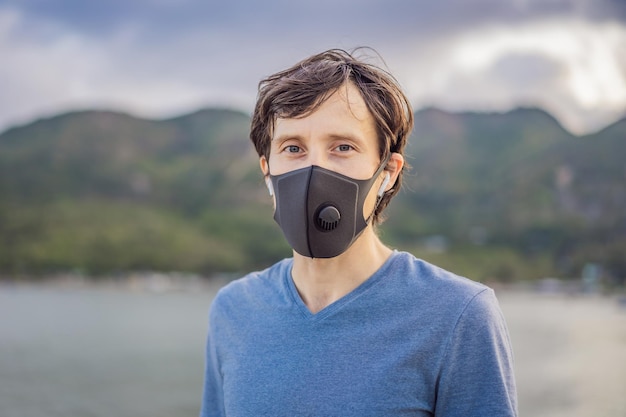 Young man in medical mask performing some workouts in the park during coronavirus quarantine