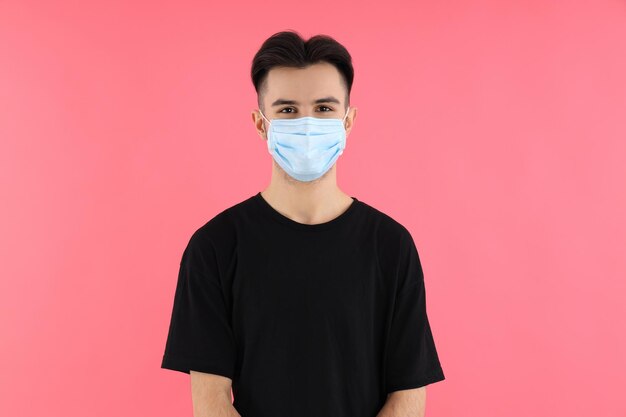 Young man in medical mask on pink background