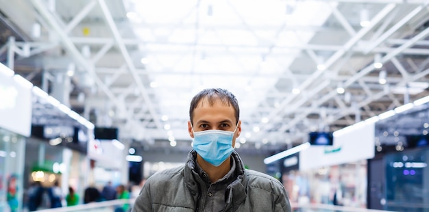 Un giovane con una maschera medica in un centro commerciale. l'uomo mascherato si protegge dall'epidemia del virus cinese 