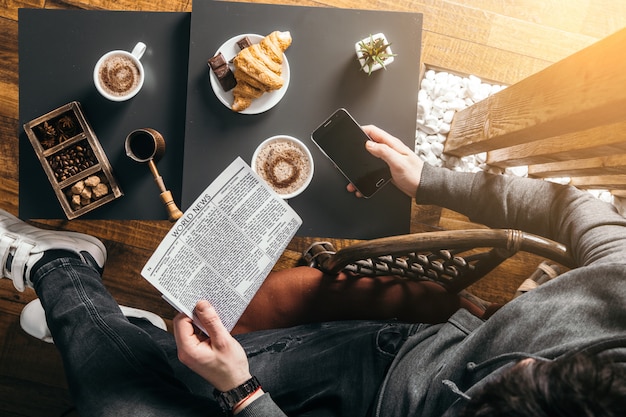 Young man in morning cafe drink coffee and read daily news