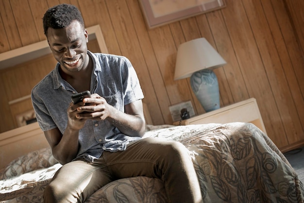 A young man in a motel room checking his smart phone