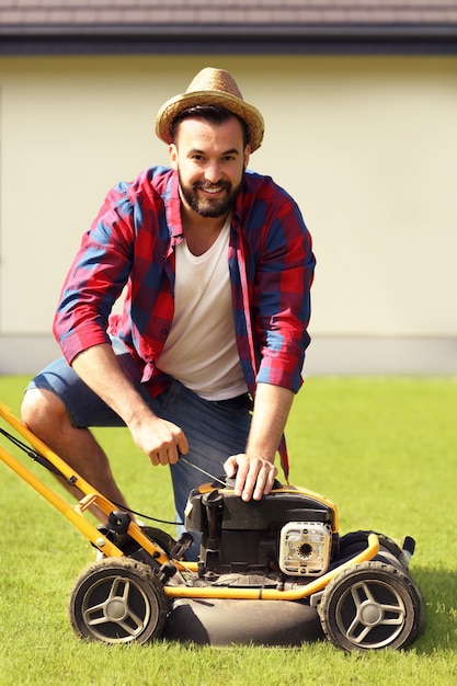 Photo a young man mowing the lawn