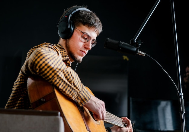 Photo young man musician singing song playing classical guitar at music studio male wearing earphones