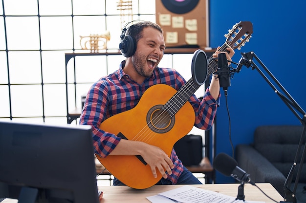 Young man musician singing song playing classical guitar at music studio