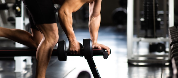 Young Man Naked bodybuilder exercising lifting with dumbbell at gym. .Gym equipment and sport concept. Fitness Healthy lifestye and workout at gym concept.