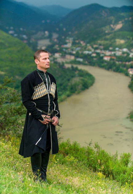 A young man in the national dress of Georgia against the background of the mountains.