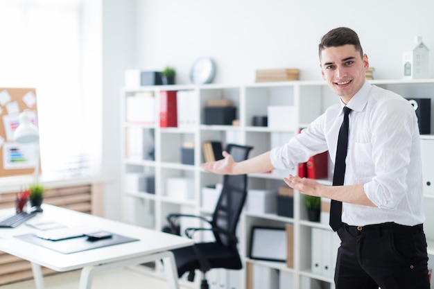 A young man in the office invites you to sit down at the table.