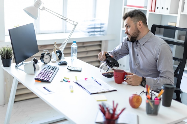 A young man in the office sits at the table