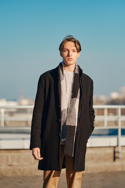 Young man in old wool coat, scarf and short trousers outdoor.