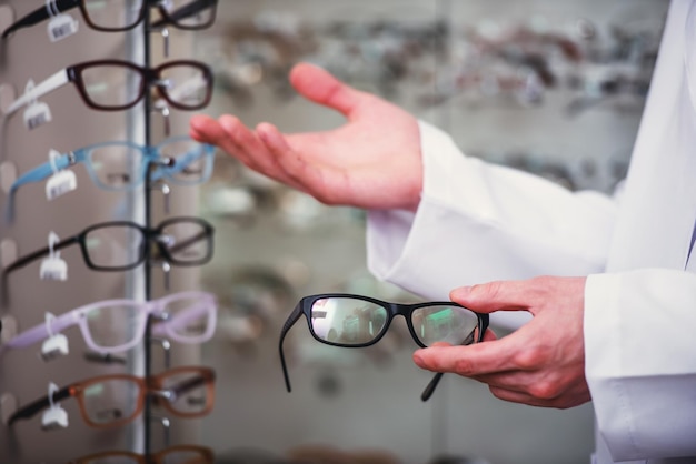 Young man only hands at optician with glasses is showing a glasses