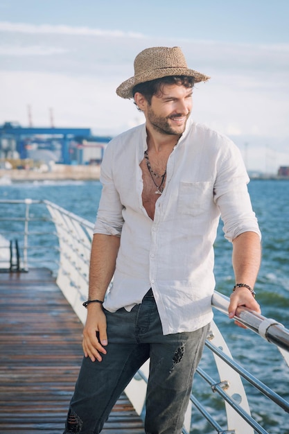 Young man outdoor portrait in hat near the sea in big city