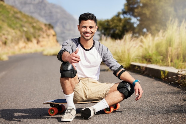 Young man outdoor skateboard and skater with fitness on country road with smile in portrait and extreme sport happiness exercise and skating gen z male and hobby with training and sports