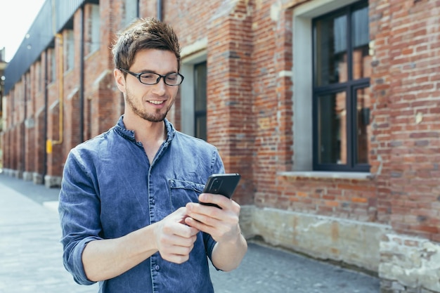 Young man outside student campus student enjoys phone smiling