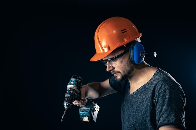 Photo a young man in overalls protective helmet hard hat hold electric drill