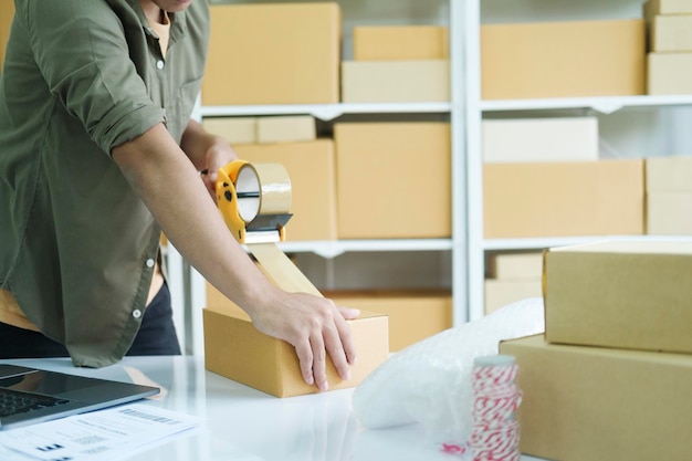 Young man packing product in box for online order xA