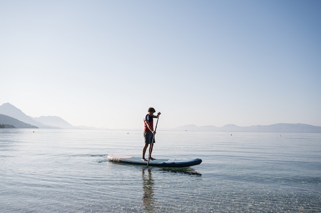 Young man paddling on sup board