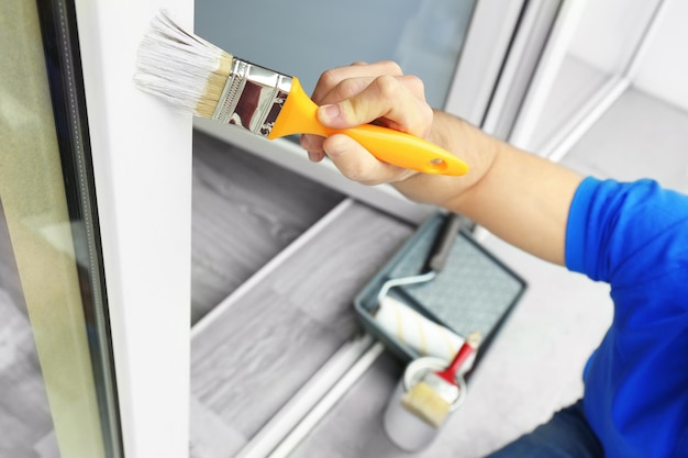 Young man painting window at home closeup