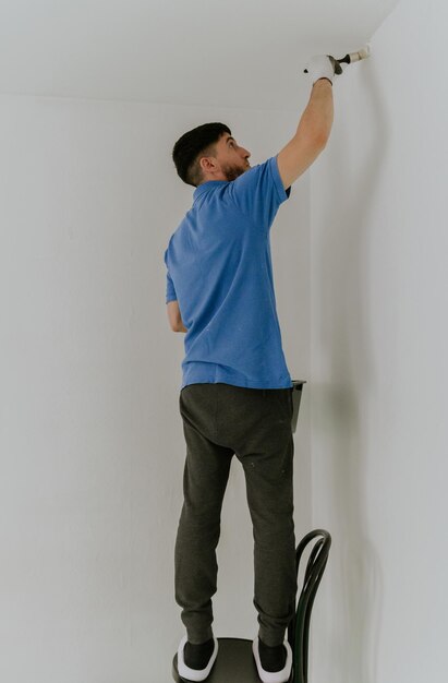 A young man paints the wall with a brush