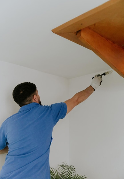 A young man paints the wall with a brush