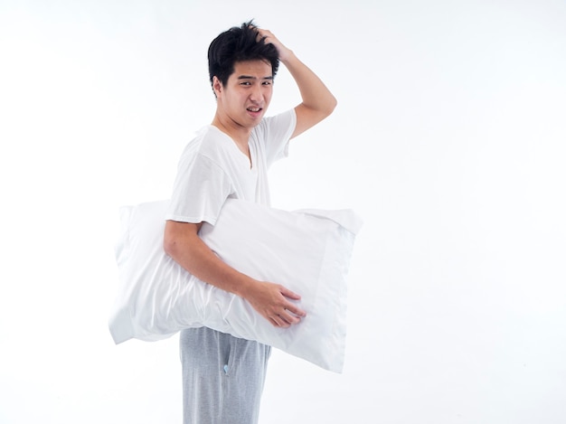 Young man in pajamas embracing white pillow isolated