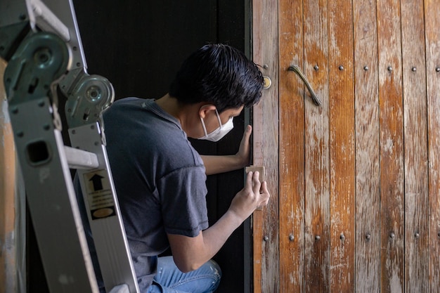 Photo young man passing sandpaper to wooden door