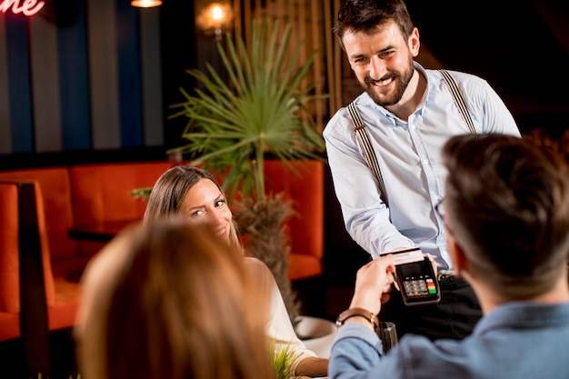 Young man paying with contactless credit card in the restaurant