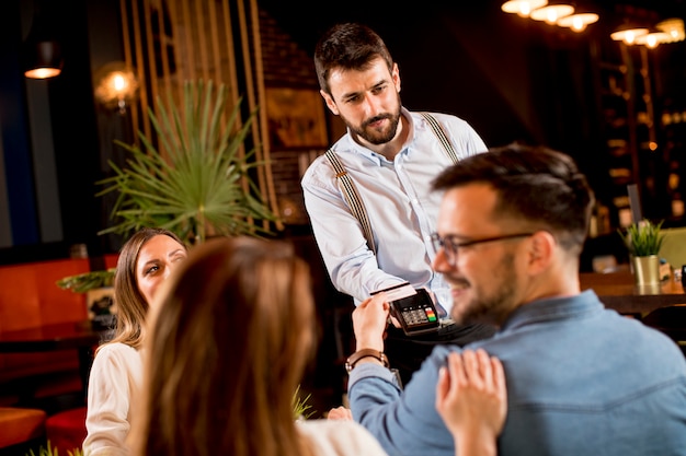 Young man paying with contactless credit card in the restaurant