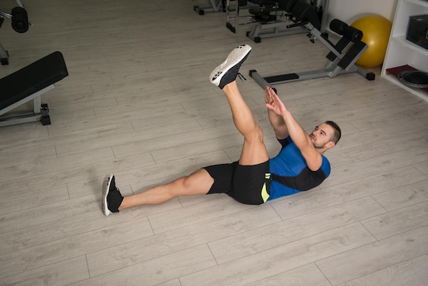 Young Man Performing Abdominal Exercise On Floor