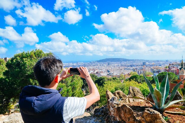 写真 携帯電話で都市風景を撮影する若い男性