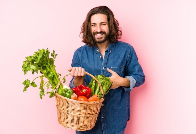 若い男が笑って、楽しんで彼の庭から有機野菜を選んでいます。